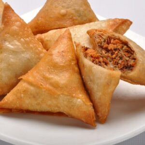 Crispy Vegetable Samosa: Golden, triangular pastry filled with spiced potatoes and peas. Ideal for a quick, flavorful bite.